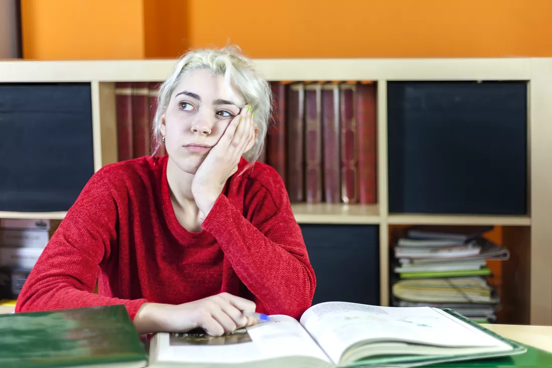 boredom-young-woman-with-hand-chin-sitting-library