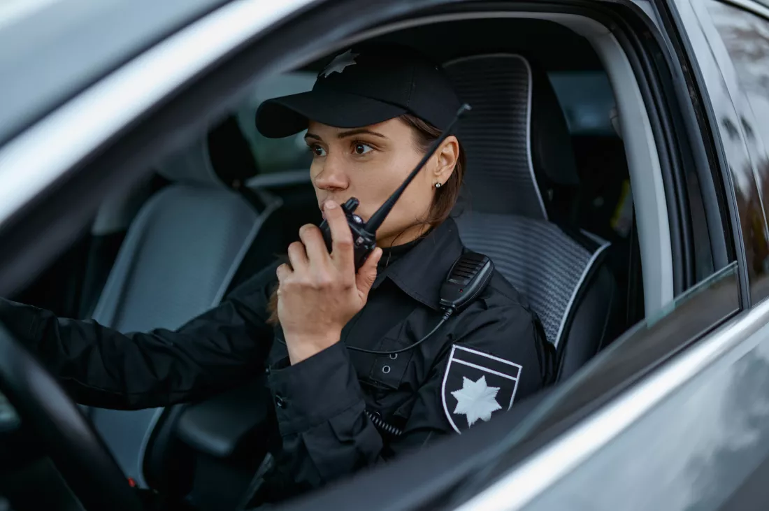 policewoman-using-radio-patrolling-street-car